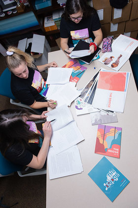 Three students around a table, editing the bridge