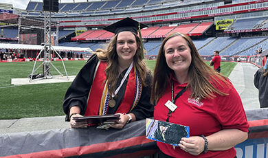 A graduate presents a donation to a BSU staff member at Gillette Stadium.