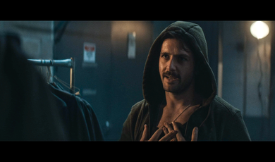 A man wearing a hood talks to another person