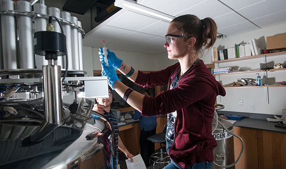 a BSU chemistry student working with a large piece of equipment with another student and a faculty member