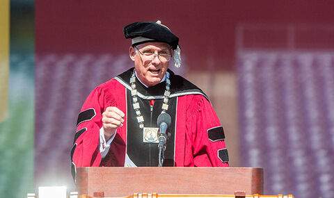 BSU President Fred Clark speaking at the Commencement podium wearing his academic regalia