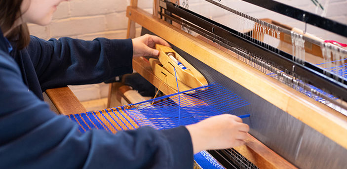 close up of a BSU student weaving on a loom
