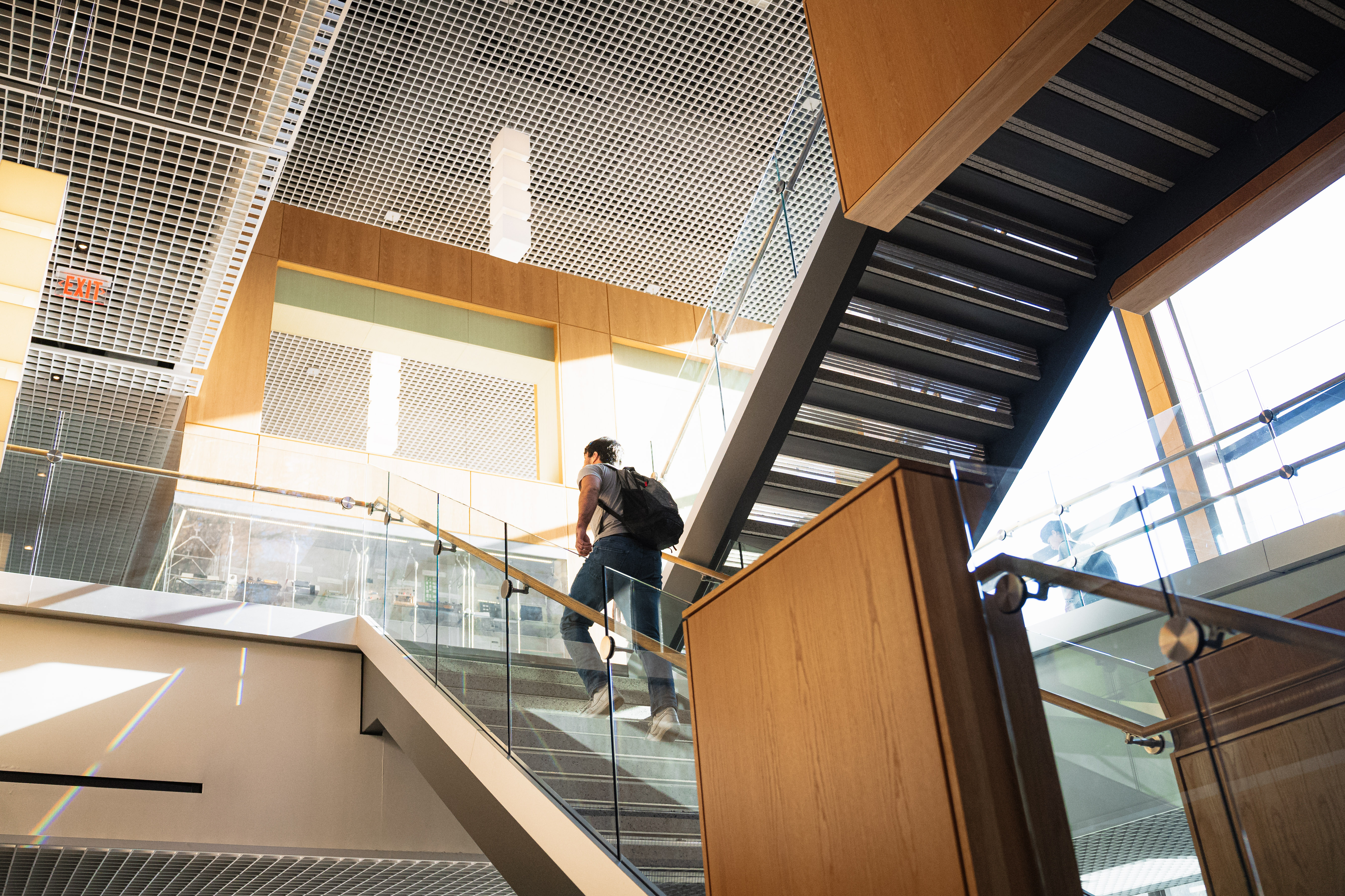 A student climbs a sunlit staircase in DMF