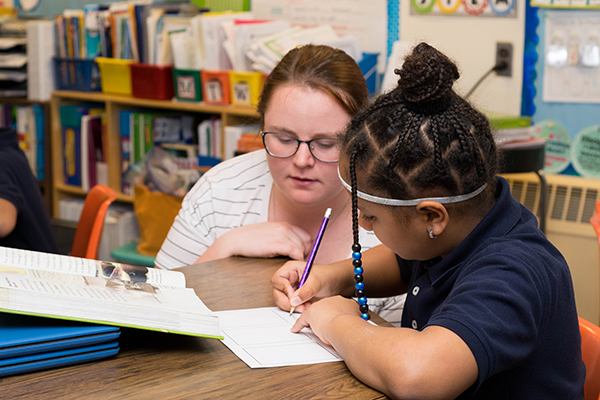 a BSU student helping a young student with a reading and writing activity