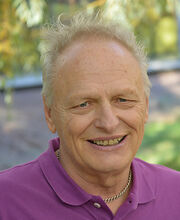 Joseph D'Adamo smiling with short wavy gray hair and wearing a purple polo shirt