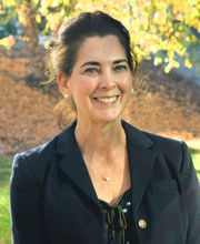 Dr. Kathleen Ferris with long dark hair pulled back wearing a black blazer over a black top