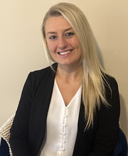 Chelsea Pilling smiling with long straight blonde hair wearing a v-neck white blouse and a black blazer