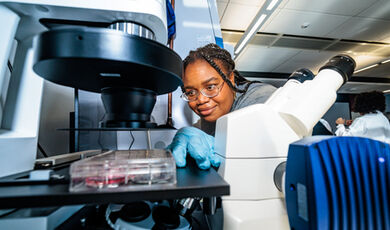 A student adjusts a sample under a microscope.