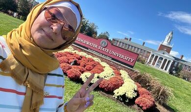 Buthina stands in front of a red BSU sign with Boyden Hall in the background.