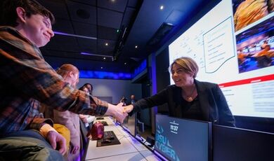 Maura Healey shakes hands with a student in the cyber range.