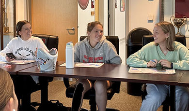 Three students work together while sitting at a table.