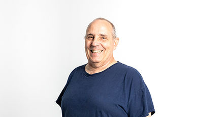 Ronald Pace smiles while standing in front of a white background