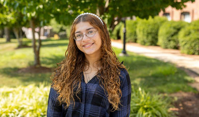 Portrait photo of Sofie De Coste standing in front of trees and grass on a sunny day.