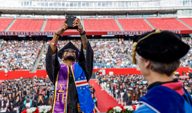 A graduate takes a selfie of the crowd from the commencement stage.