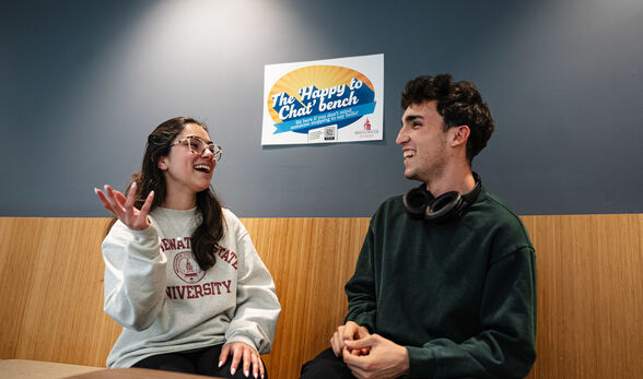 Two students at the 'Happy to Chat' Bench having a conversation
