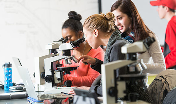 3 female students viewing slides on microscopes