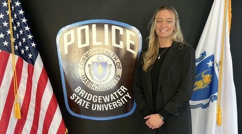 A woman stands next to a Police sign and smiles
