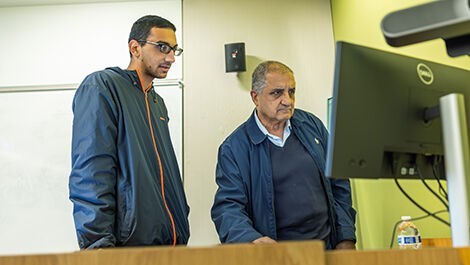 A professor and student work at a computer.