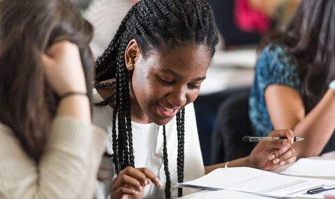 students sitting at a table in a classroom reviewing papers