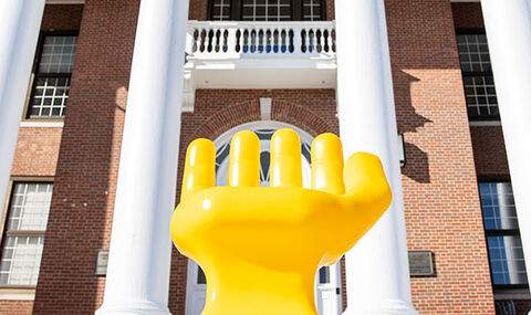 A yellow hand sculpture outside of Boyden Hall