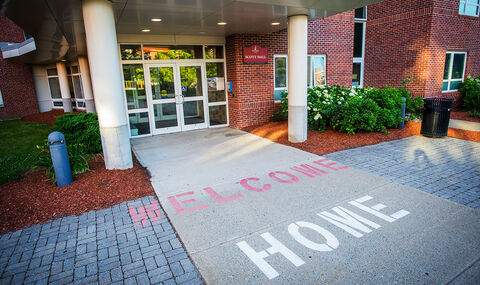 The words "Welcome Home" are painted in red and white on the walkway leading into Scott Hall