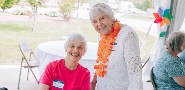 Two people smile for the camera at a Senior College event.