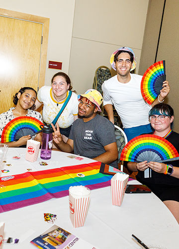 Five students with rainbow fans smiling at BSU's Big Queer Welcome event